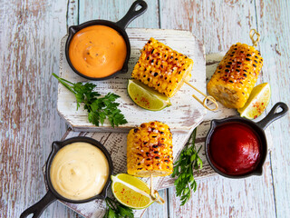 grilled yellow corn with spices lime white red orange sauce portion top view