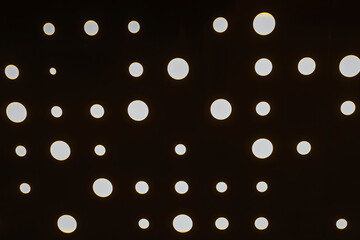 aluminum sheet with holes and light at the back. dark texture with round slits. corrugated metal sheet in the interior with lighting