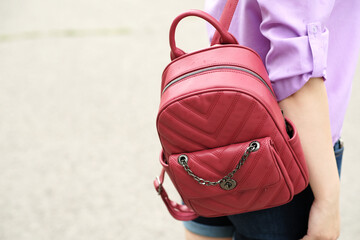 Red casual backpack hanging on unrecognizable woman. Close up.