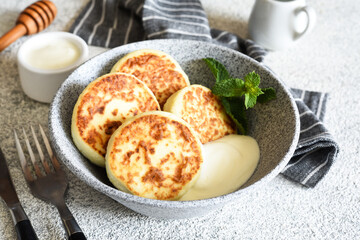 Homemade cheesecakes in a concrete plate and sour cream. Word sauce and cottage cheese casserole.