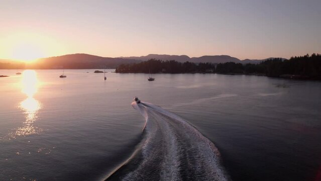 Aerial footage motor boat at sunset, Whiffen Spit, Sooke Harbour, calm water, ocean, Vancouver Island. 5.4K TO 4K 24FPS