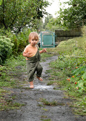 Baby with bare feet runs through a puddle