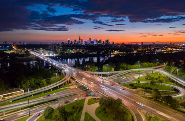 Fototapeta na wymiar Stunning sunset skyline, aerial Warsaw, Poland. Drone shot of city downtown business center skyscrapers in background. Highway bridge over river and driving cars, amazing cloudscape evening dusk night