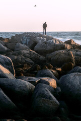 joven meditando en las rocas de la orilla de la playa