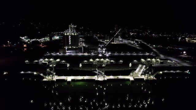Night aerial drone footage of marine terminal and bulk shipping terminal, silos, grain elevators, freight vessels, North Vancouver, BC. 4K 24FPS.