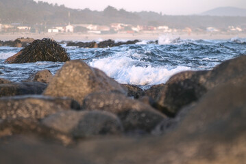 Obraz premium durante el ocaso se ven las olas rompiendo en las rocas de la playa