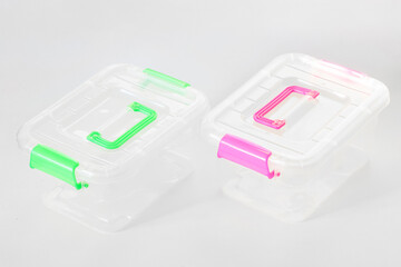 Two transparent plastic containers with multi-colored lids on a white background. Copy space.