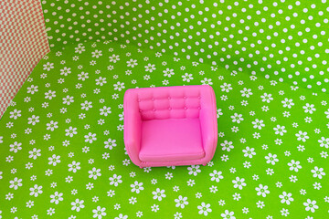A colorful 70s style room with a plastic pink sofa, floors and walls in green and pink pattern....