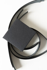 coil paper strips with pile of black paper tiles on white