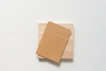 plain brown paper pocket envelope on a square wooden block on paper