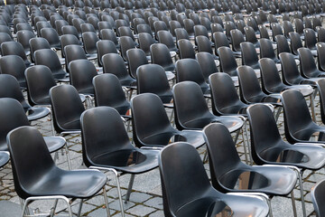 Empty portable plastic chairs for spectators stand on the street