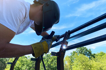 Metal welding in industrial production, a man in a welding mask welds a metal structure