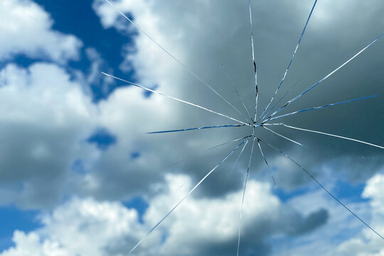 Cracked glass against the blue sky, windshield crack