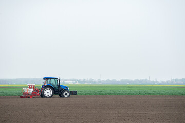 Obraz premium Farmer with tractor sowing on agricultural field on sunny spring day