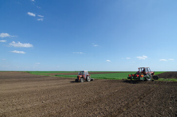 Obraz premium Farmer with tractor sowing on agricultural field on sunny spring day