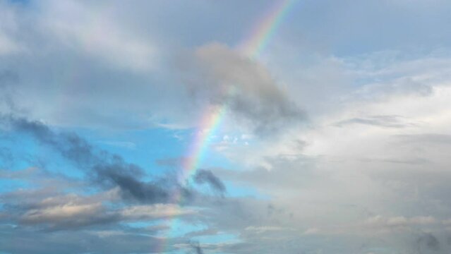 Rainbow on blue sky with clouds. Nobody