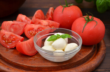 mini mozzarella cheese in a bowl and tomatoes close-up