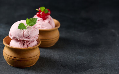 Pink scoops of popsicles with red currants on a black table. Ice cream