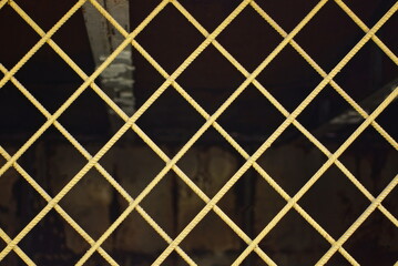 yellow metal texture of iron bars in the pattern in the wall of the fence on the street