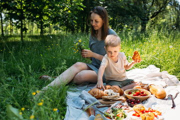 Family mom and son on picnic. Smiling and enjoying summer on blanket in park.