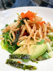 Seaweed salad with fried wontons fish eggs and avocado at a restaurant