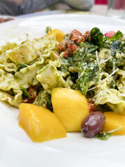 Pesto pasta with mango and olives at a restaurant 