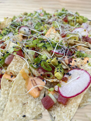 Loaded tuna poke nachos with radishes sprouts aioli at a restaurant