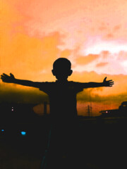 Silhouette of defocused boy enjoying the freedom of the sunset,immortalized from the roof of the house