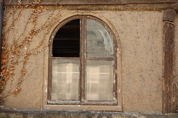 Fototapeta na wymiar Arch window with broken glass in old building in europe