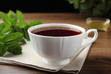 Cup of hot aromatic tea with mint on wooden table