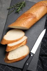 Cut tasty baguette with knife on grey table, flat lay