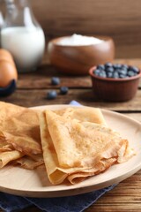 Delicious crepes served on wooden table, closeup. Space for text