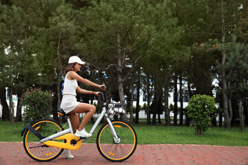 Fototapeta premium Beautiful young woman riding bicycle on lane outdoors. Space for text