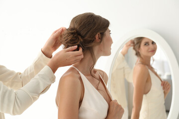 Hair stylist preparing bride for her wedding indoors