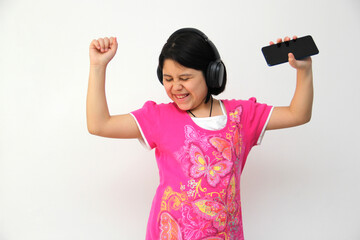 10-year-old Hispanic girl listens to music on her headphones connected to her cell phone dances,...