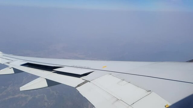 flight window view in air turing for landing with hazy blue sky at morning