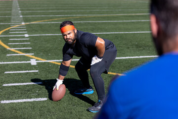 Biracial gay male practicing for American flag football game on turf field - Powered by Adobe