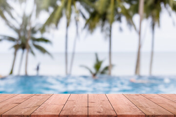 Empty wood table top and blurred swimming pool in tropical resort in summer banner background - can used for display or montage your products.