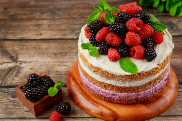 A sponge cake topped with fresh raspberries and blackberries.