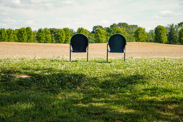 Lawn chairs on the side of a farm field