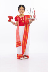 Happy bengali girl in traditional sari holding puja thali and dhunachi
