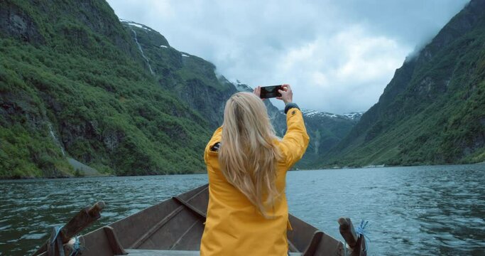 Traveling woman taking photos on phone, looking at view on a boat ride and enjoying the scenery on the sea. Female taking pictures for social media, riding on the ocean water and exploring a lake