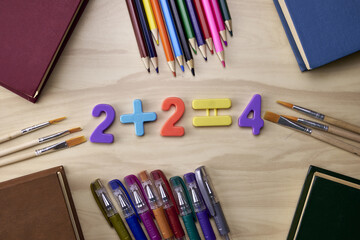 arithmetic example 2 plus 2 equals 4 on the table around the book pencils fountain pens the concept...