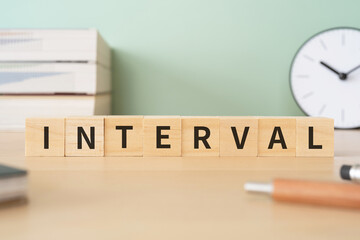 インターバル・間隔のイメージ｜「INTERVAL」と書かれたブロックが置かれたデスク
