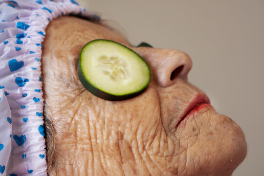 Relaxed Older Woman With Cucumber Slices On Her Eyes. Beauty And Skin Care Procedures.