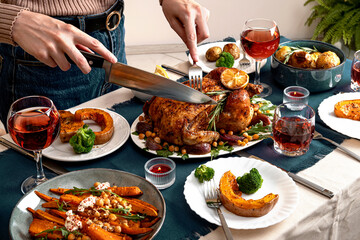 People celebrating Thanksgiving Day. Woman cutting meat for family and friends on table. Traditional holiday stuffed baked chicken dinner and vegetable. Family party or gathering.