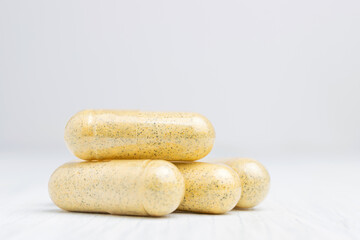 Yellow herbal capsules on white table, medication treatment, alternative medicine, close-up view
