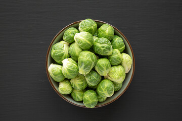 Raw Organic Brussel Sprouts in a Bowl on a black background, top view. Flat lay, overhead, from above.