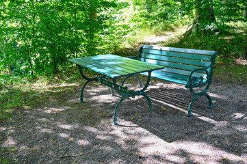 green bench standing in a shaded area in garden