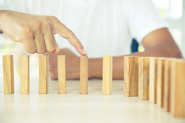 Close-up hand prevent wooden block not falling domino concepts of financial risk management and strategic planning and business challenge plan.